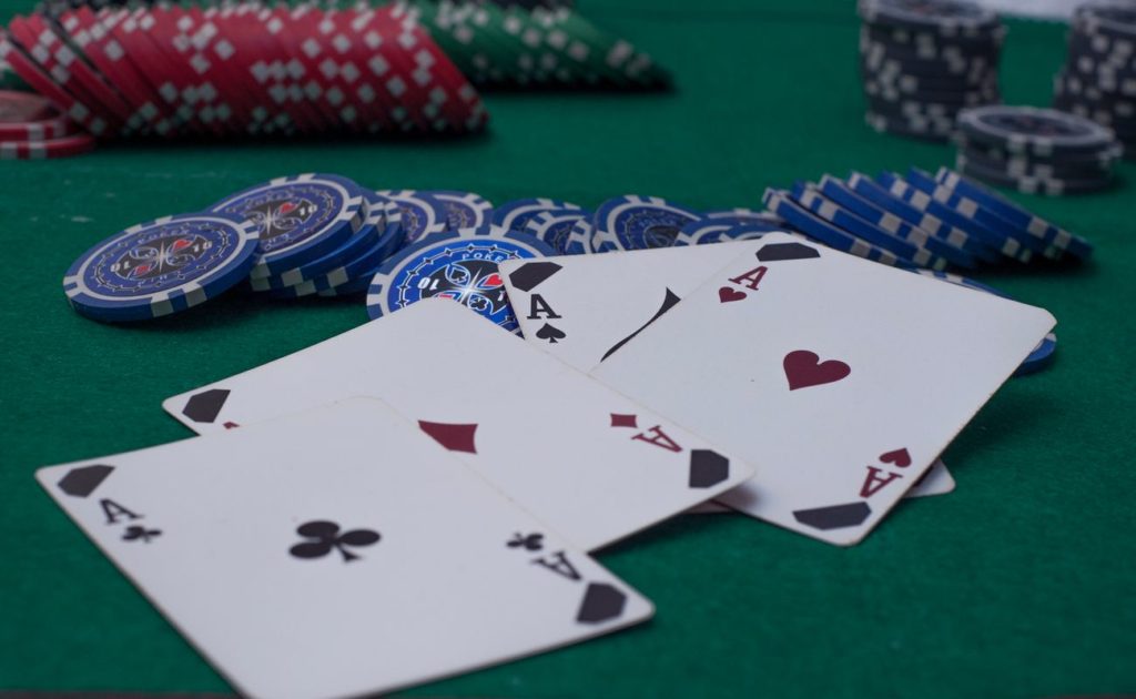 4 Aces scattered over blue poker chips on a green poker table